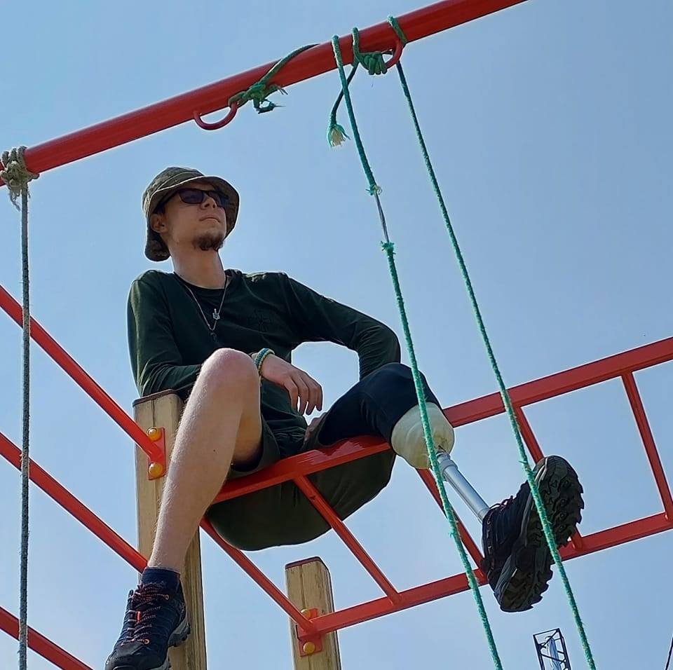 На рисунку зображено ветерана війни Андрія Голопапа, який сидить на металевому рукоході. Замість лівої ноги він має металевий протез.