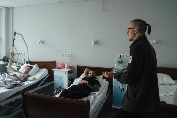 На рисунку зображено ветерана війни Андрія Голопапа, який відвідує Захисників та Захисниць, які проходять лікування у шпиталях Києва. Вони лежать у ліжках та ведуть бесіду з Андрієм.
